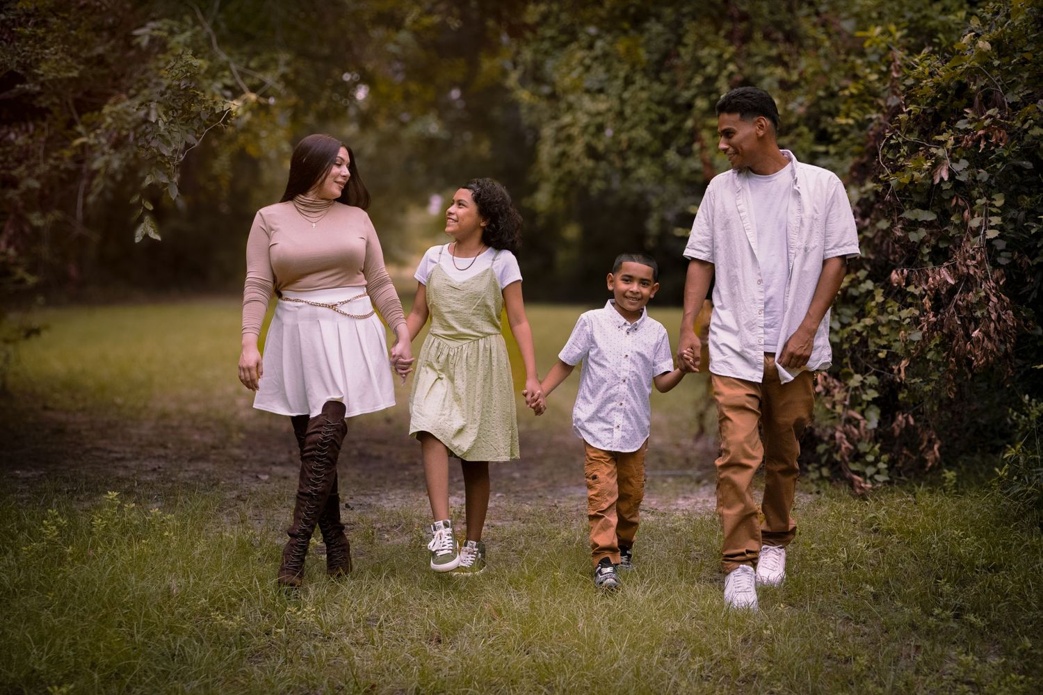 A family of four takes a casual stroll together on a wooded path.