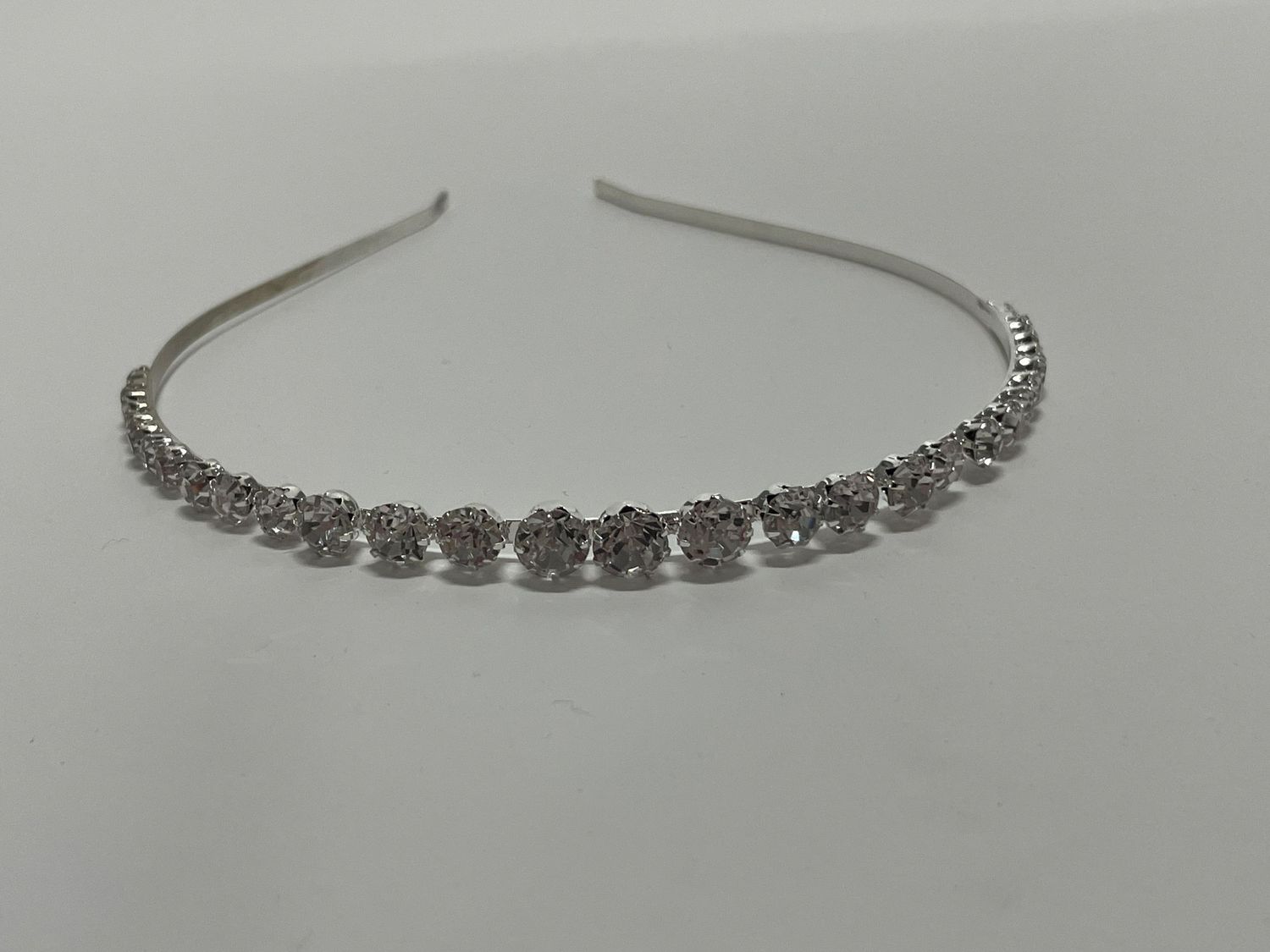 Crystal-encrusted silver headband with evenly spaced floral designs along the band.