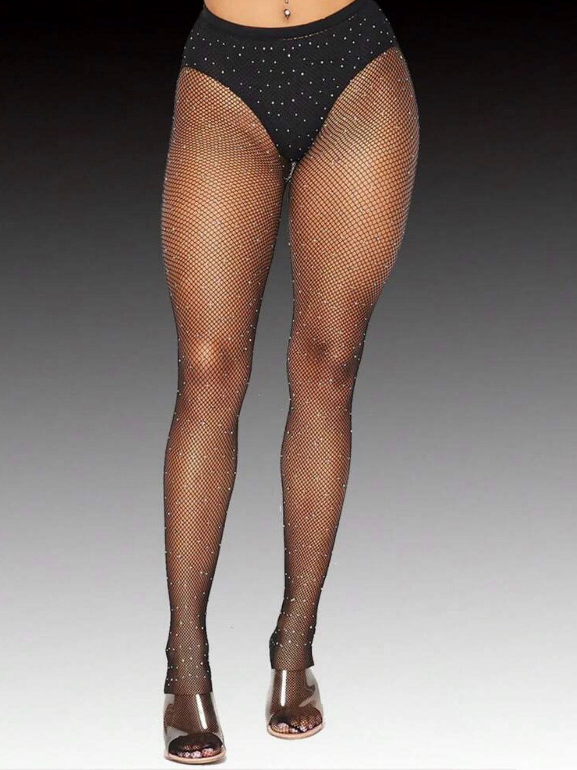 Black sparkly tights and heels on legs against dark background.