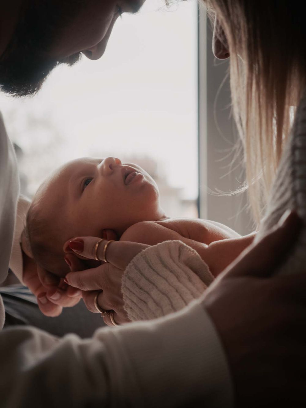 ein 4 Wochen alt baby  mit sein Eltern in einem Baby Fotoshooting bei den Eltern zuhause mit natürlichem Licht zuhause.