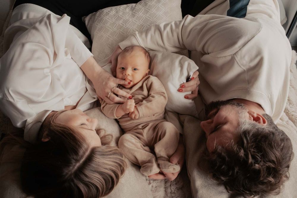 ein 4 Wochen alt baby  mit sein Eltern in einem Baby Fotoshooting bei den Eltern zuhause mit natürlichem Licht zuhause.