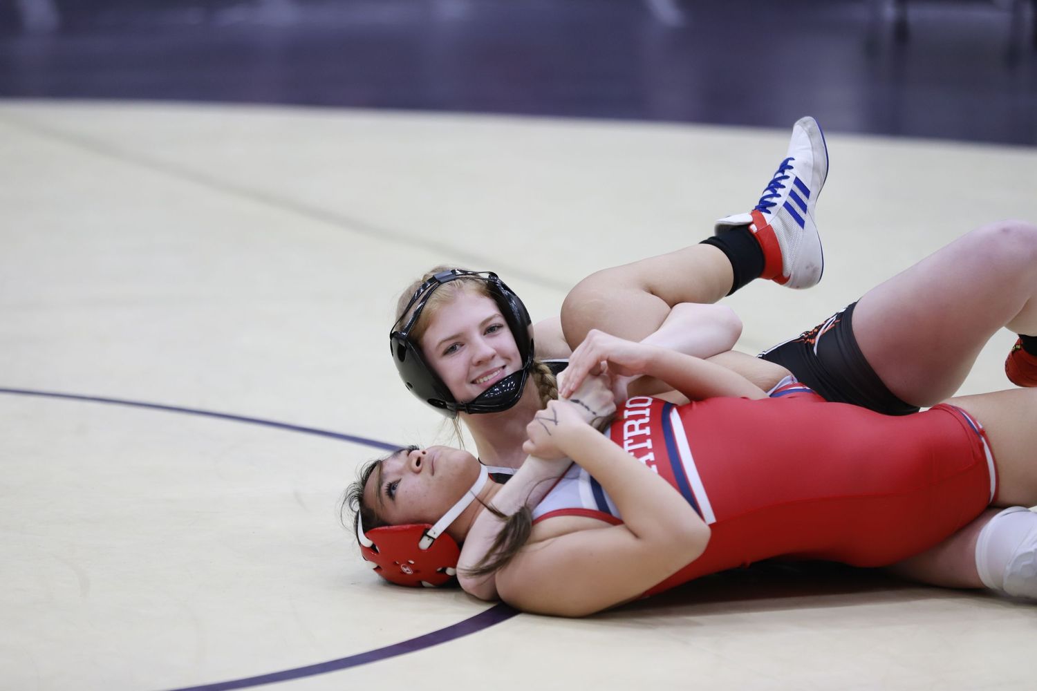 Two wrestlers compete on a gymnasium mat during a match. Oviedo, Florida