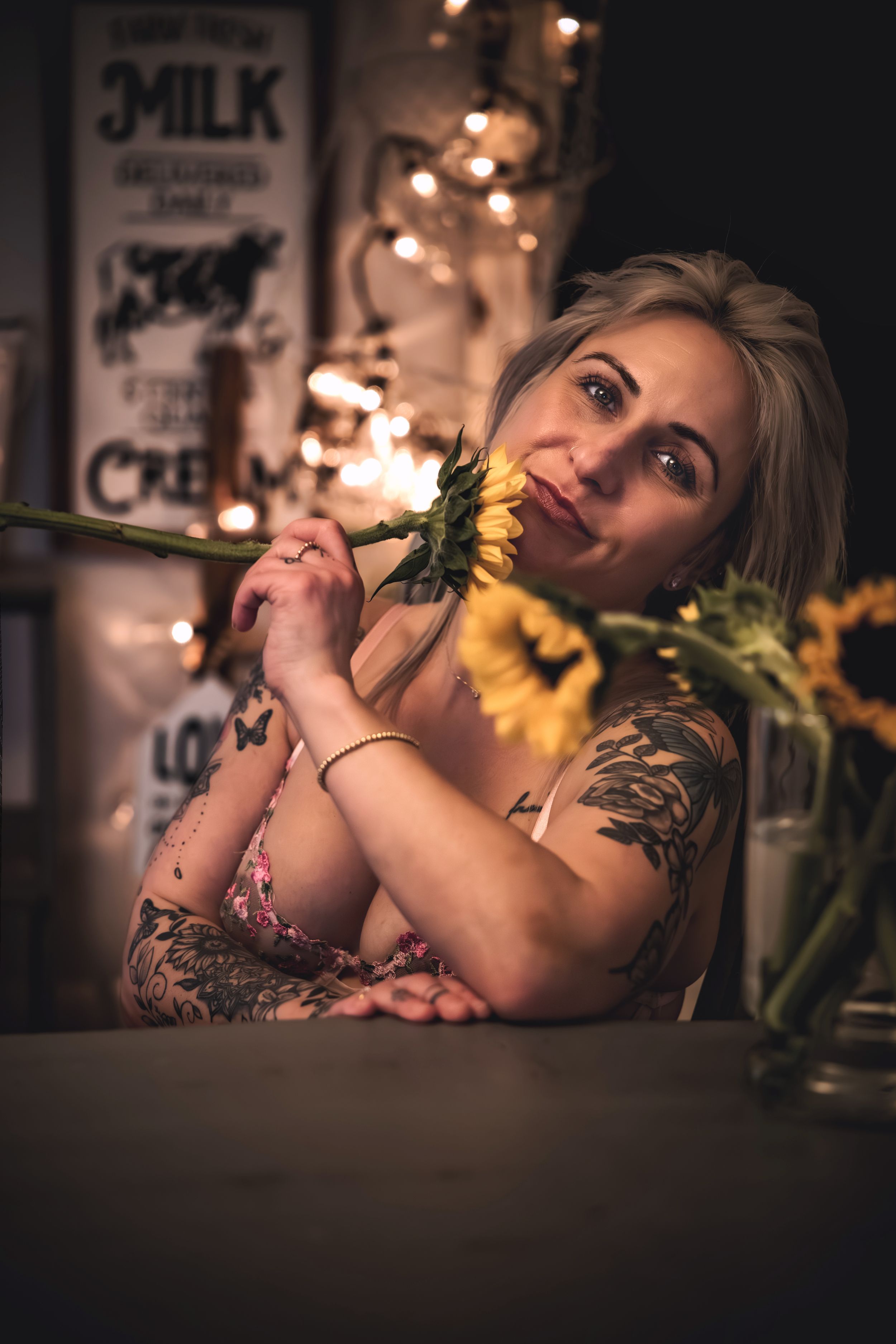 Creative moody portrait with sunflowers in dark setting with warm ambient lighting.