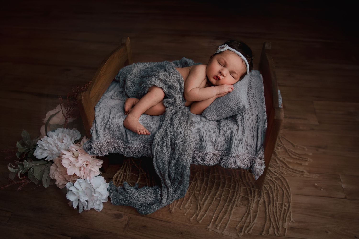 newborn baby laying in tiny bed prop