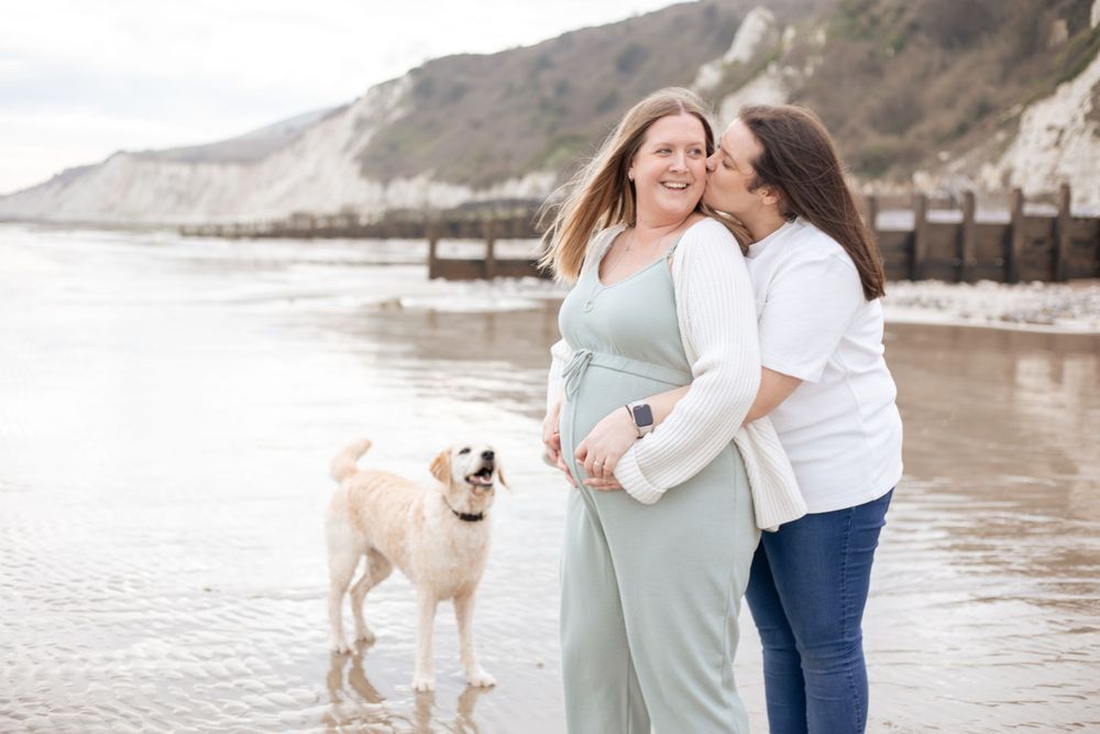 maternity photoshoot with two women on eastbourne beach with dog in background