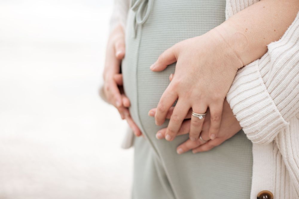 close up of two sets of hands on pregnant belly