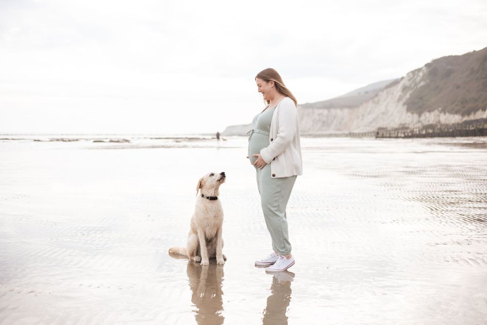pregnant woman looking at her dog on eastbourne beach