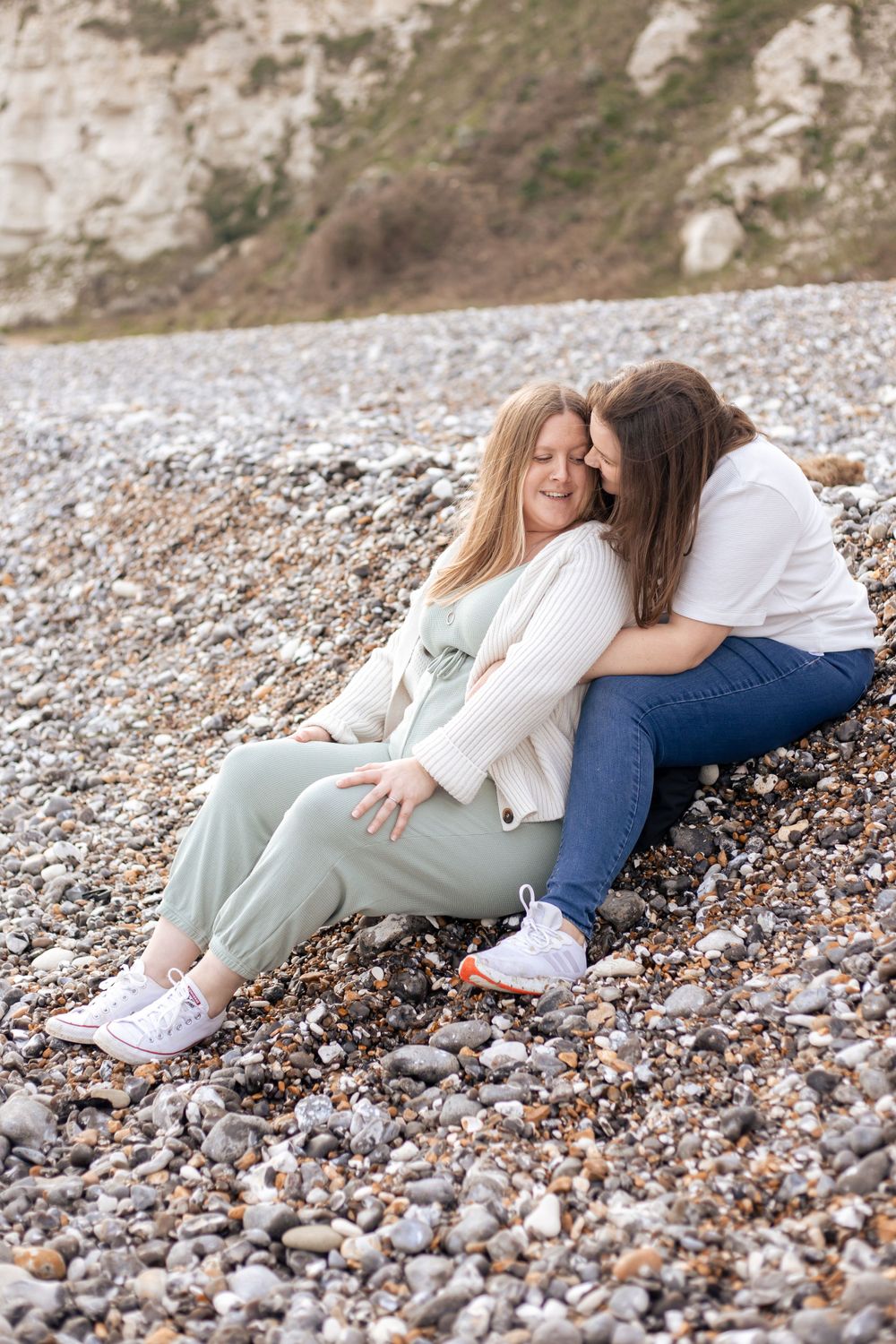 two women embracing during maternity photoshoot on eastbourne beach