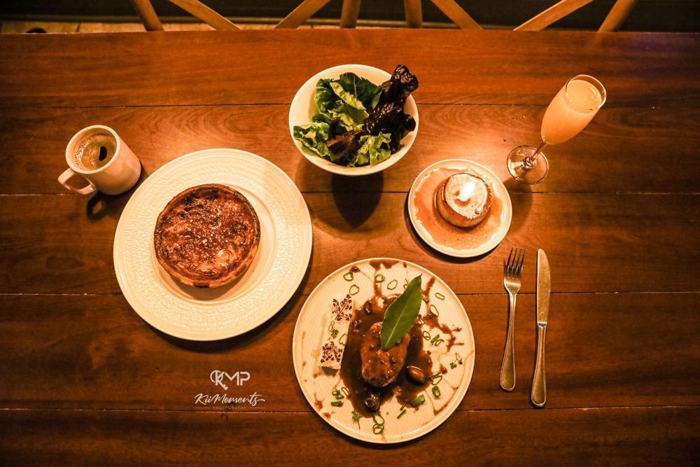 Overhead view of plated dinner with wine and salad on wooden table.