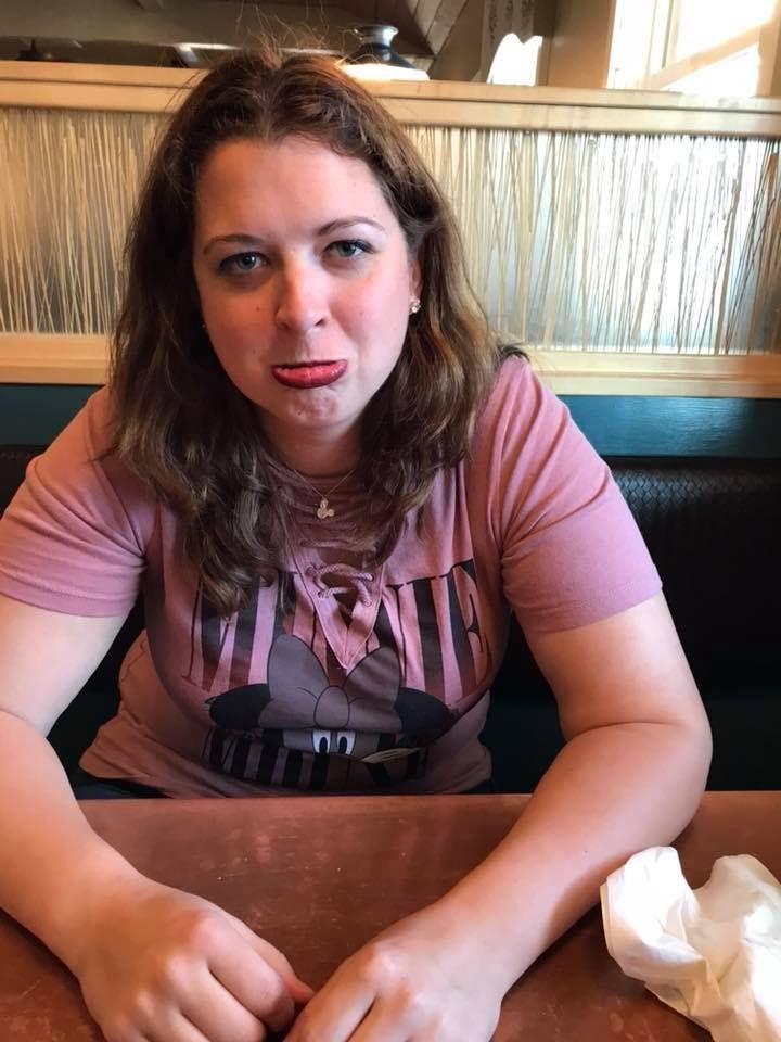 Person sitting in restaurant booth wearing pink t-shirt.