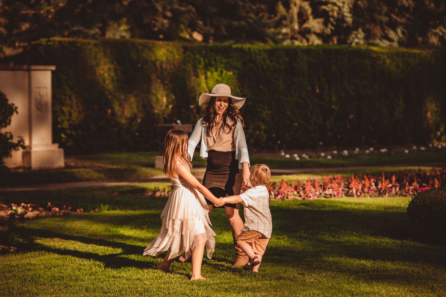 People dancing and playing together on a sunny lawn in front of a hedge. Family Photography