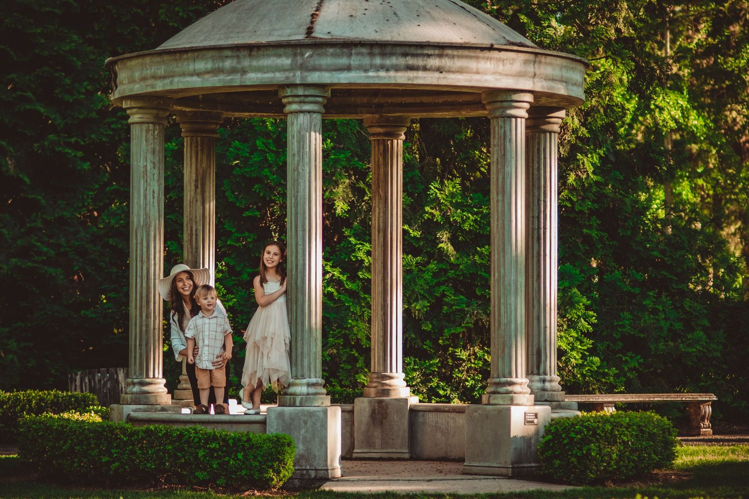 Two figures standing in an elegant white gazebo surrounded by lush gardens. Family Photography