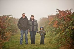 A family stands together on a foggy autumn path surrounded by colorful foliage.