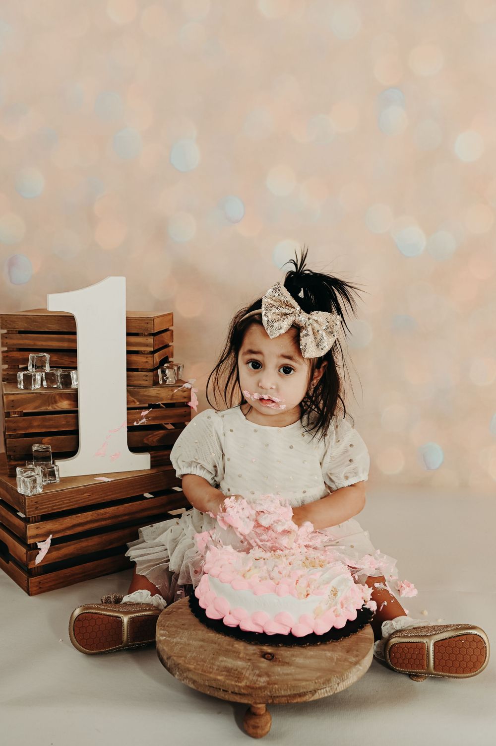 First birthday cake smash setup with wooden crates and pink cake on rustic stool.