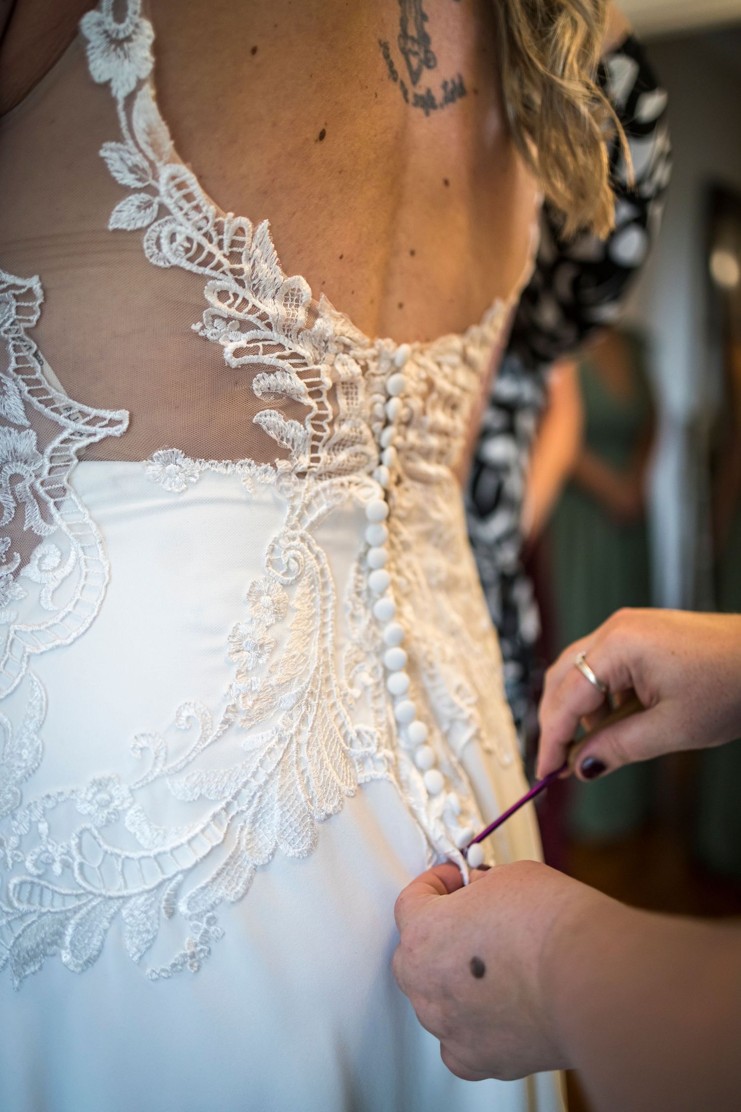 Close-up of intricate lace detail and buttons on back of white wedding dress.