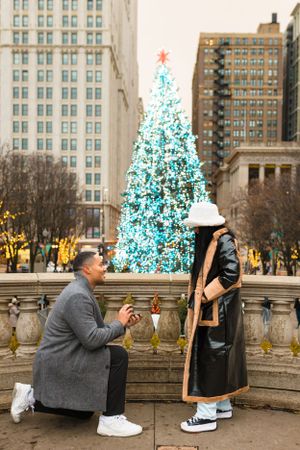 Proposal in Chicago at Millenium Park near christmas with Christmas tree in the background