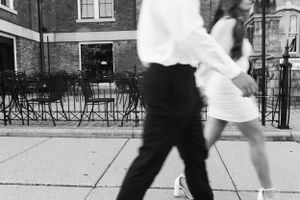 man and woman in black and white image walk down street. Street in focus, walking slightly blurred
