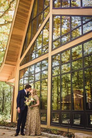 Couple kiss in front of their wedding chapel in the woods in Franklin Milwaukee Wisconsin