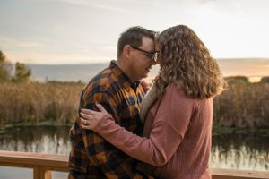 Couple embraces in front of lake in Minneapolis Minnesota. Engagement
