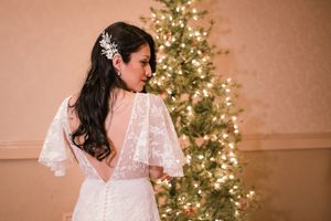 Bride faces away and looks back in her Minneapolis Christmas wedding with Christmas tree in the back. Shows off dress