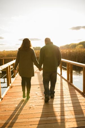 couple walks off into the sunset on a pier on lake in minneapolis minnesota