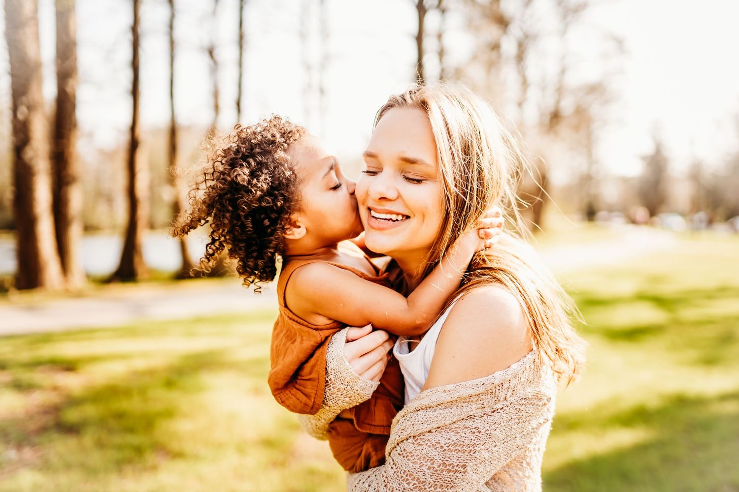 a toddler girl gives her mom a kiss on the cheek