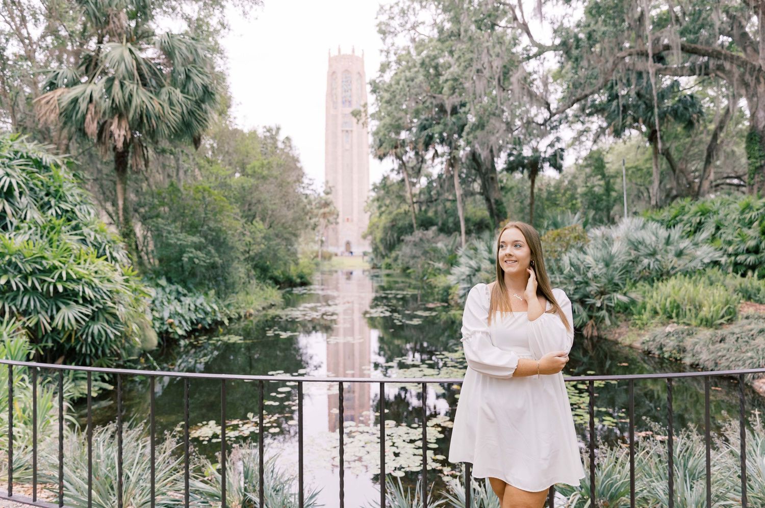 A garden setting with lush greenery, palm trees, and a decorative bridge or walkway in a scenic outdoor location.