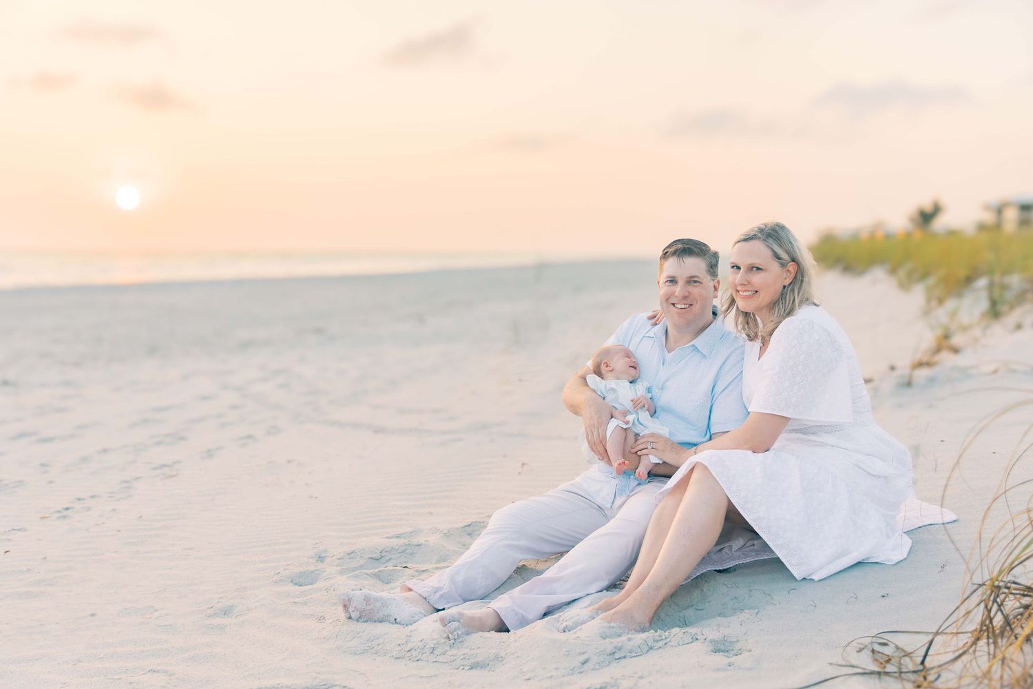A serene beach scene at sunset with soft pink and blue tones.