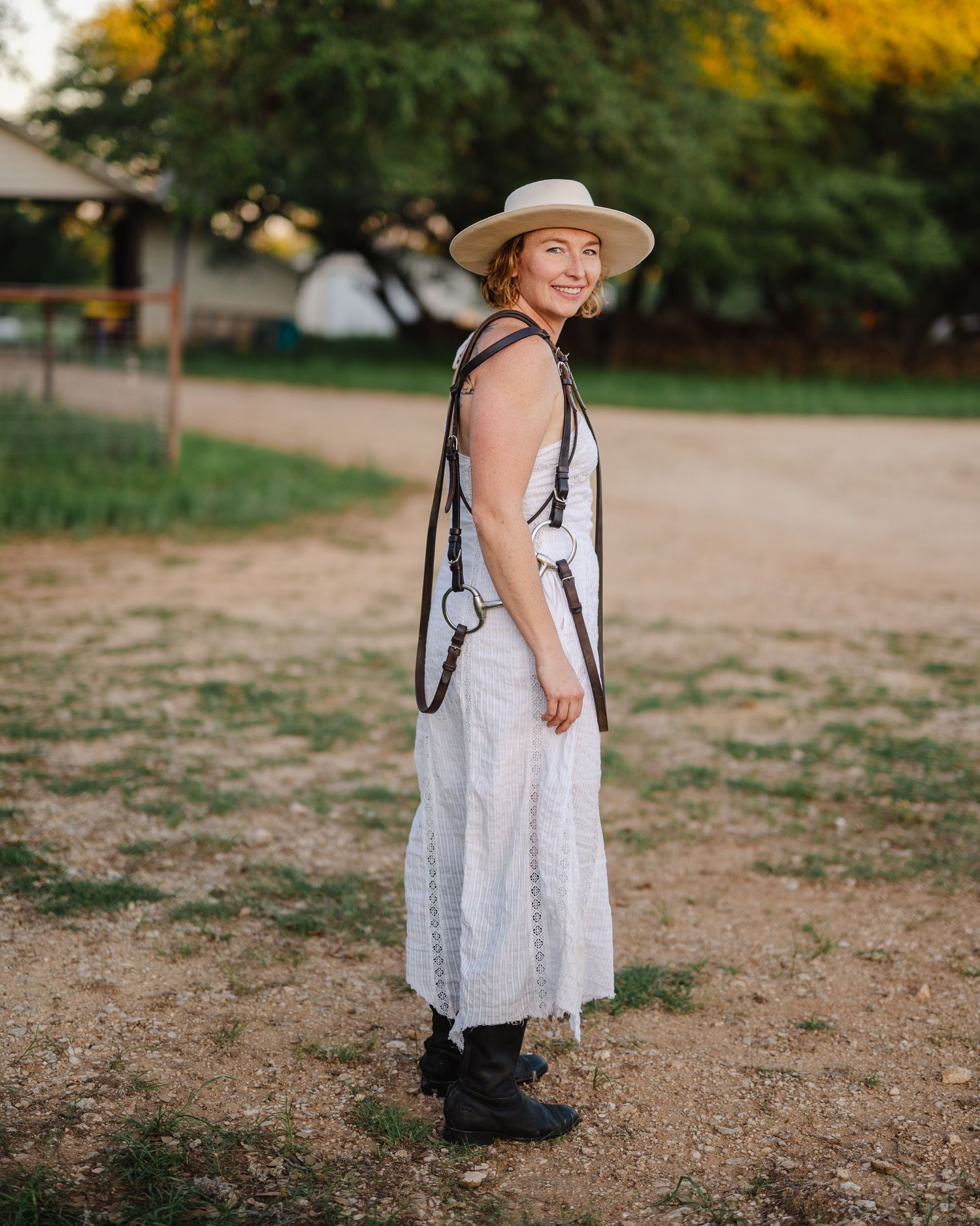 A person in a flowing white dress walks joyfully through a rustic outdoor setting.