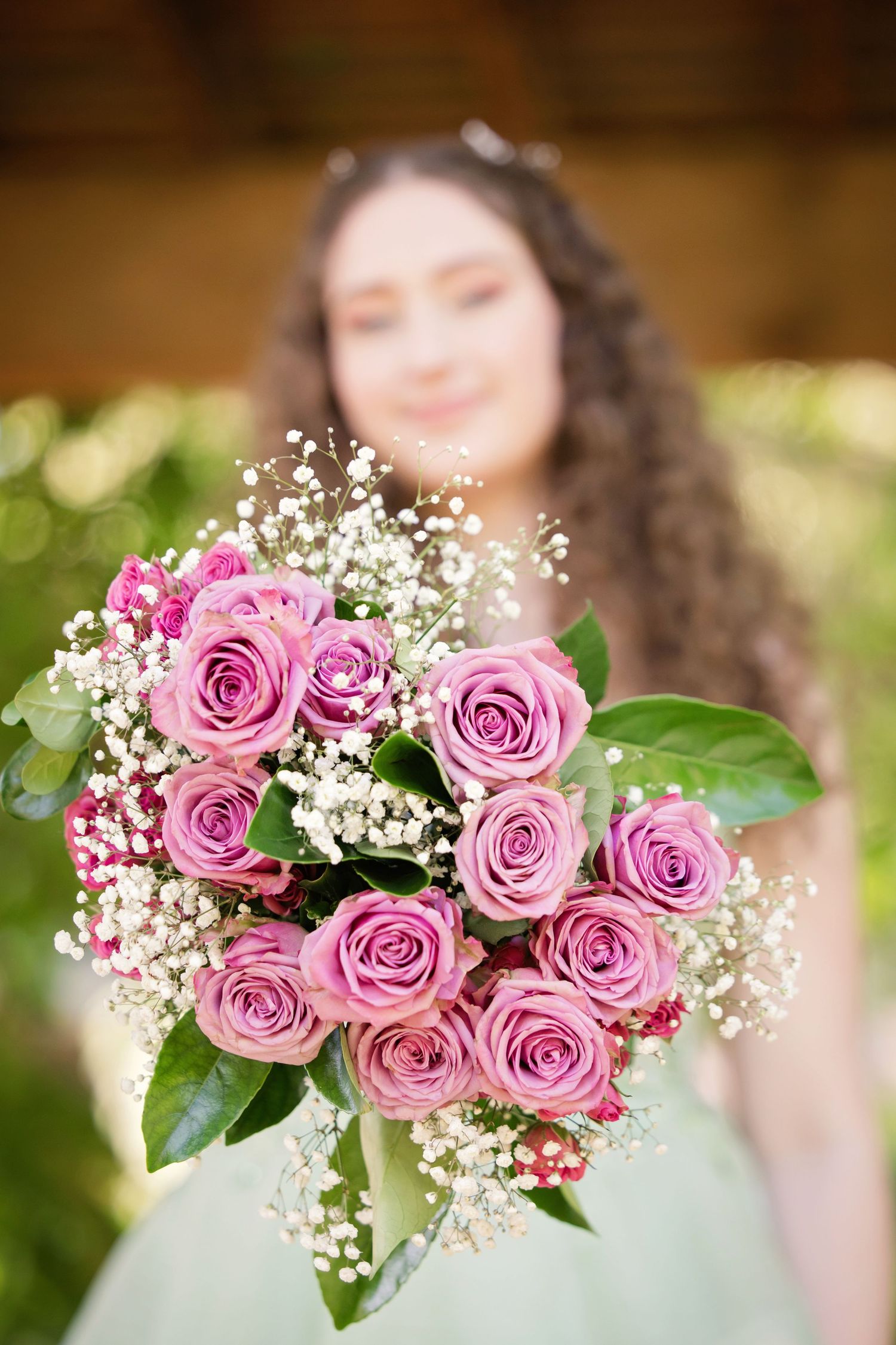 Beautiful bouquet with lavender roses and baby's breath held against a soft mint green dress in sunlit garden in Grapevine, TX