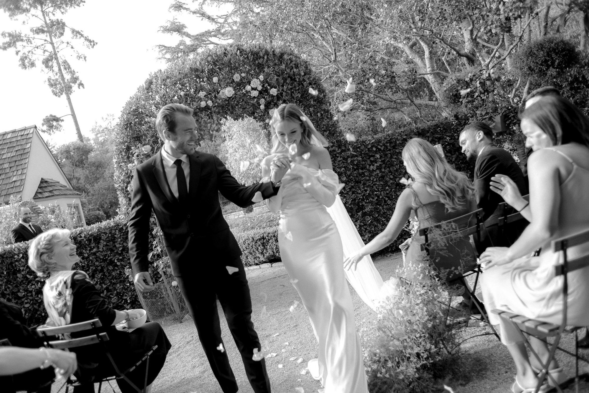 Wedding party celebrating outdoors with water splashing in black and white photography.