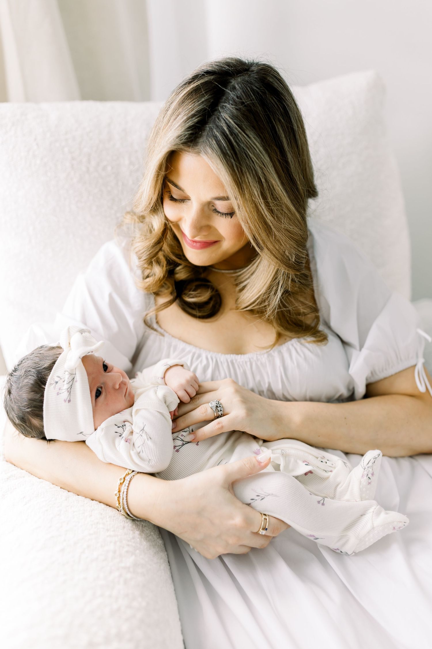 A gentle moment with a newborn baby being cradled in a white dress.