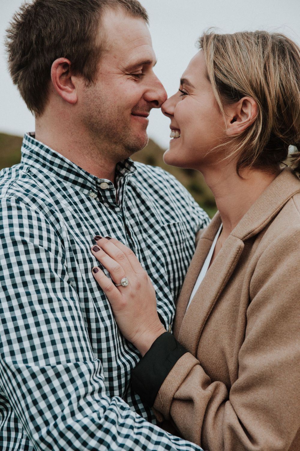 close up of engaged couple nuzzling and engagement ring