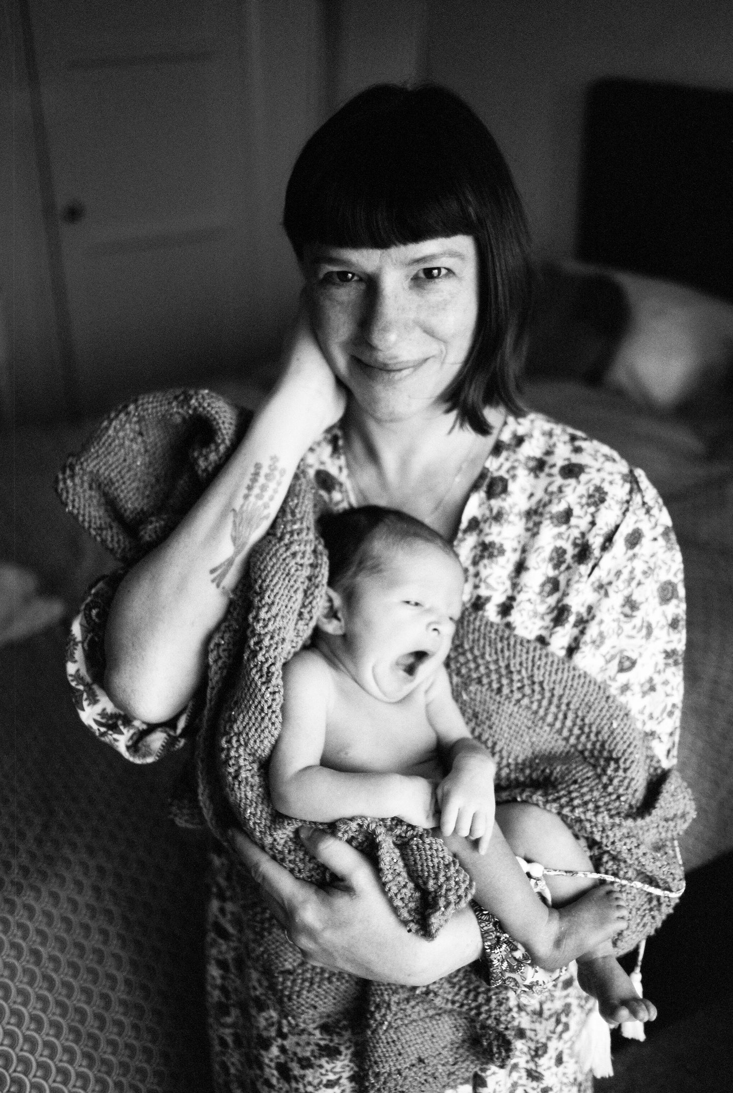 Black and white photos of parent and infant sharing tender moments with a knit blanket.
