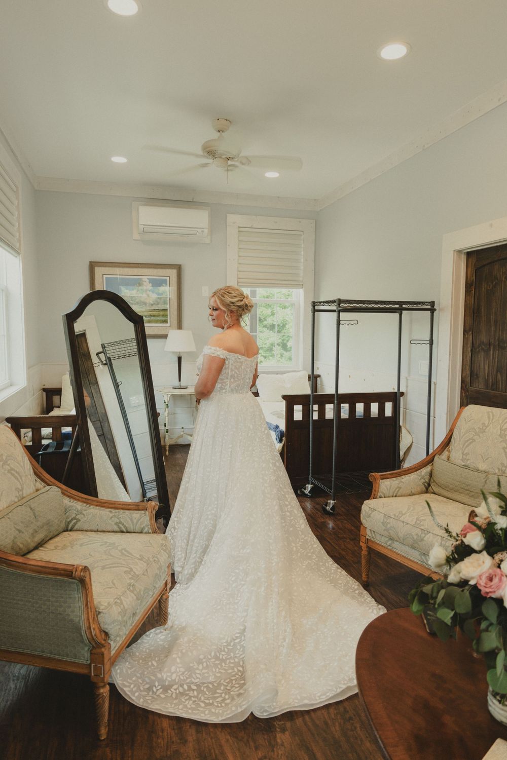 Wedding dress with long train reflected in vintage mirror in bridal suite.