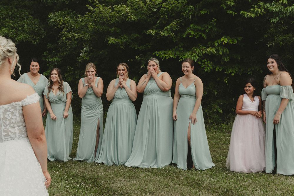 Bridesmaids in mint green dresses react emotionally to first look at bride.