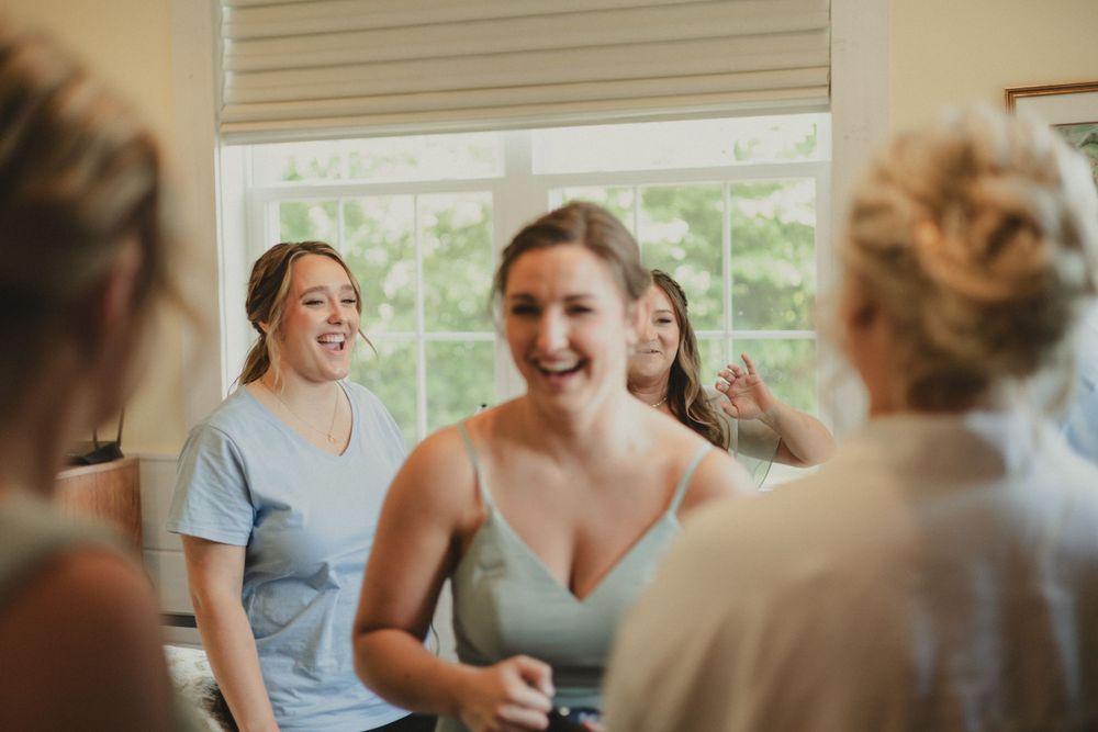 Candid moment of bridesmaids laughing together during wedding preparations.