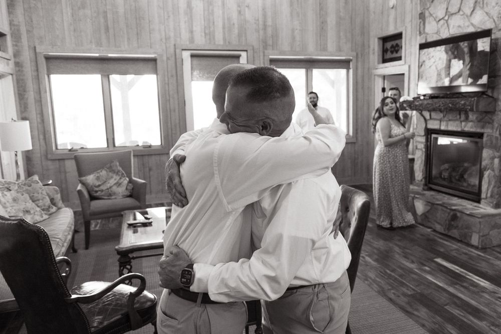 Emotional embrace captured in black and white inside a rustic living room setting.