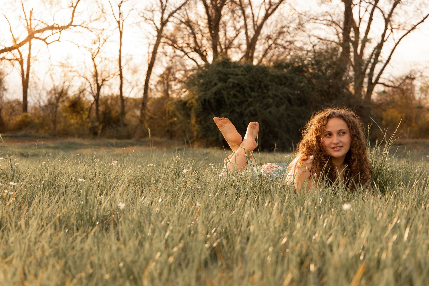 Two friends pose with flowers in a golden field during sunset.