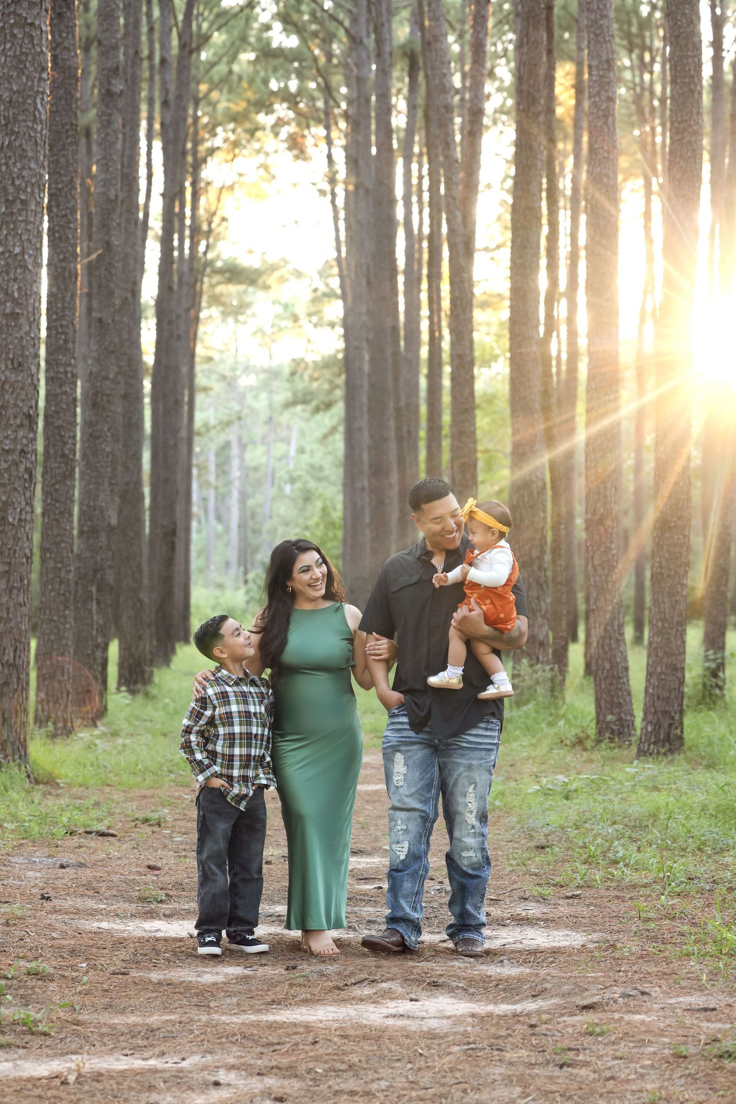 Family standing in shallow water during sunset photoshoot.