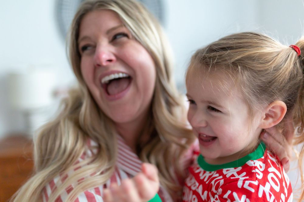 Candid laughing moment in matching holiday stripe and red pattern pajamas.