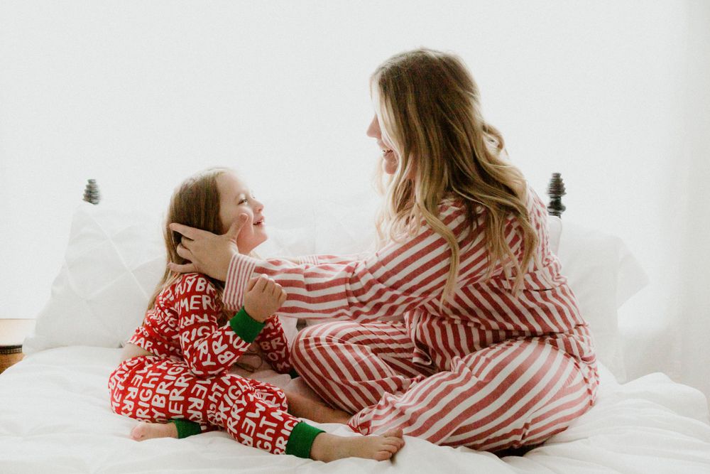 Cozy morning scene with matching striped and red patterned pajamas on white bedding.
