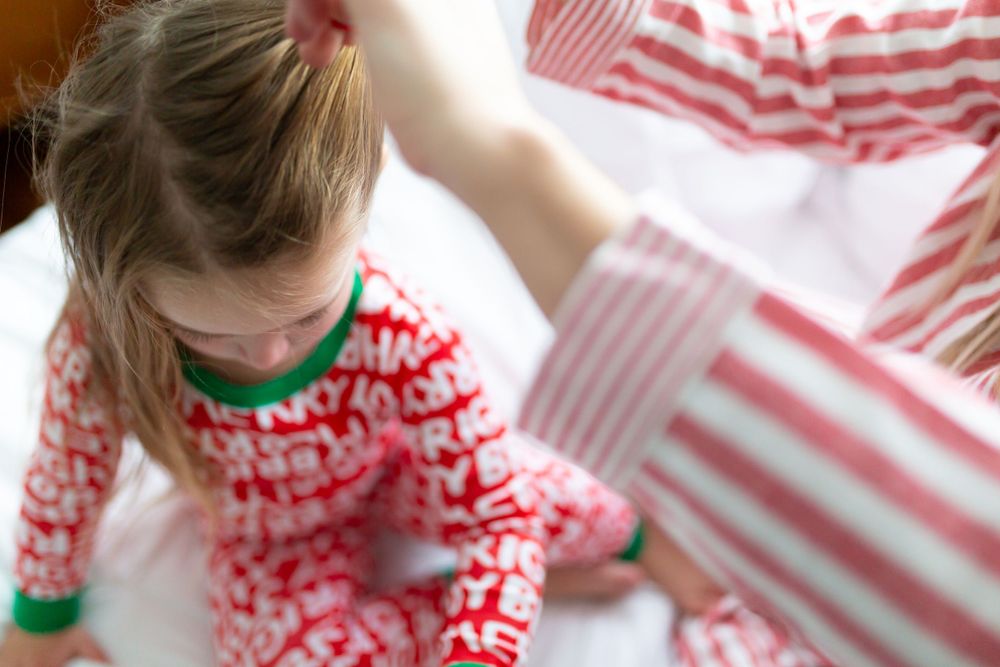 Close-up of festive red and white patterned Christmas pajamas on white bedding.