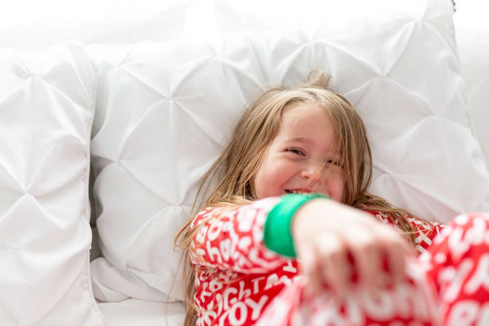 Holiday-themed moment of joyful laughter in cozy white bedding.
family photography