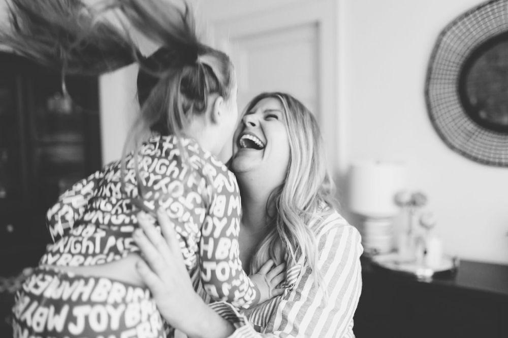 Black and white candid moment of joyful laughter and playfulness on bed.