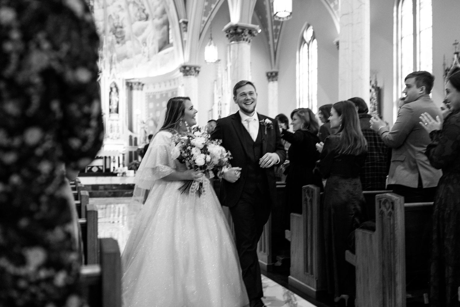 A black and white photo of a wedding ceremony inside a beautiful traditional church.