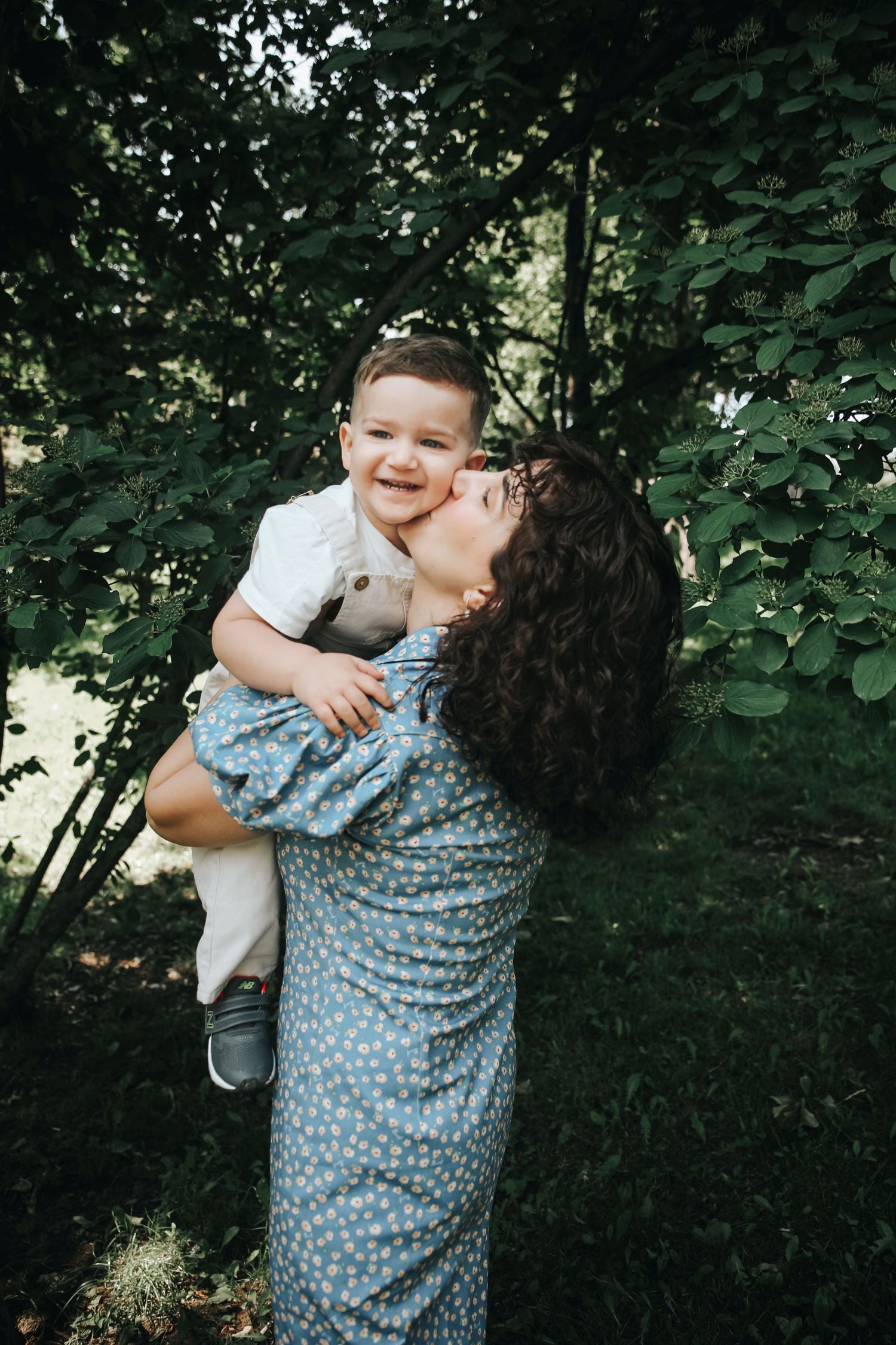 Candid outdoor family moment captured among lush green foliage.