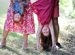 Playful family moment captured with children hanging upside down in garden setting.
