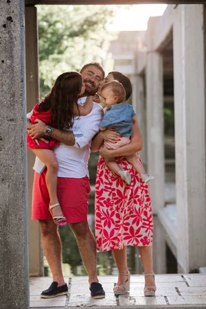 Family embracing in warm sunlight under architectural archway.