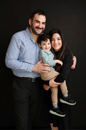 Studio portrait of family enjoying tender moment together against dark background.
